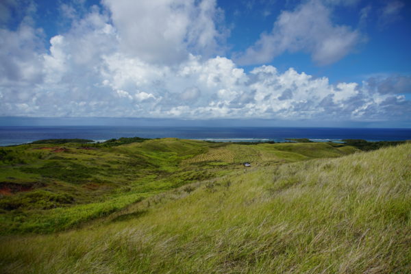 Landscape view of Guam with green hills in the foreground and the sea and clouds in the background