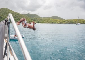 A person does a backflip into a body of water on an island