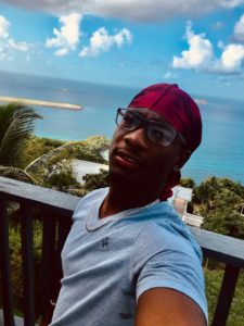 A person taking a selfie from a balcony on a tropical island near the water